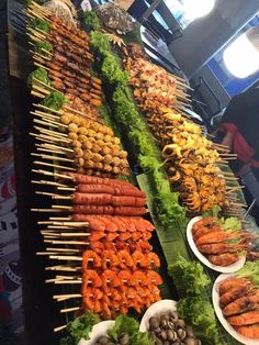 many different types of food on sticks and bowls with skewers next to each other