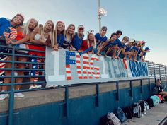 a group of young people standing on top of a blue fence next to each other