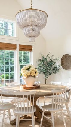 a dining room table with white chairs and a potted plant on top of it