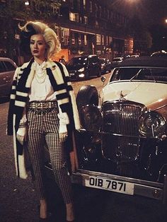 a woman standing in front of an old fashion car