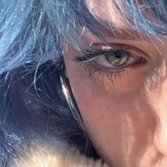 a close up of a person with blue hair and an earpiece in her hand