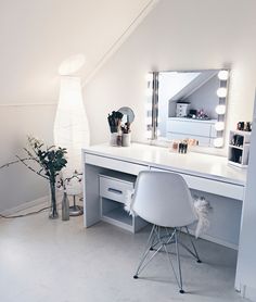 a white desk and chair in a room with a large mirror on the wall above it