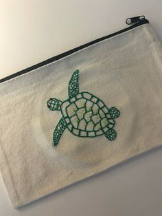 a small white bag with a green turtle embroidered on it