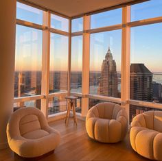 a living room filled with furniture and large windows overlooking the cityscape at sunset