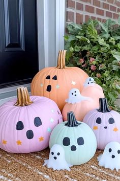 painted pumpkins sitting in front of a door with ghost faces and stars on them