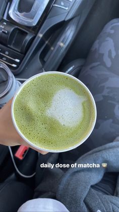 a person holding a cup in their hand while sitting in the driver's seat