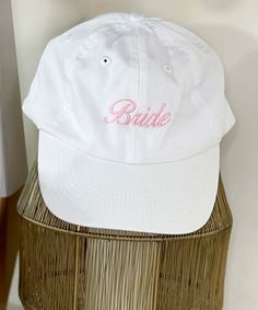 a white baseball cap with the word bride embroidered on it sitting on a bamboo basket