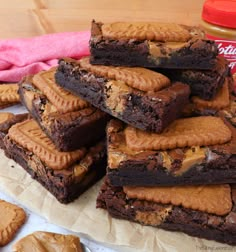 a pile of brownies sitting on top of a wooden table next to peanut butter cookies