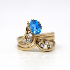 Stunning & unique vintage 14k yellow gold ring featuring a genuine swiss blue topaz gem. The asymmetrical ring contains 6 sparkling diamond accents, with an oval cut blue topaz weighing approximately 1.47 carats. A truly rare & one of a kind gemstone ring! ERA - Circa 1980s METAL / MATERIAL - 14k yellow gold, 1 genuine blue topaz gemstone (estimated 1.47 carats), 6 genuine diamonds (approx. .30 ctw, SI clarity range, near colorless) MARKINGS / HISTORY - Inside of band is stamped 14k COND Vintage Blue Oval Sapphire Ring, Vintage Yellow Gold Rings With Blue Topaz, Vintage Yellow Gold Blue Topaz Rings, Vintage Blue Topaz Ring In 14k Gold, Blue Oval Topaz Ring In 14k Gold, Oval Blue Topaz Ring In 14k Gold, Oval Topaz Ring In 14k Gold, Vintage Blue Topaz Ring For Anniversary, Vintage Oval Birthstone Diamond Ring