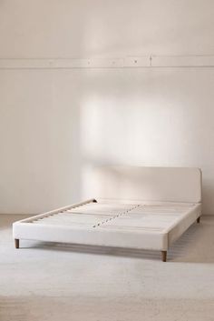 a white bed frame in an empty room with no sheets on the bottom and sides