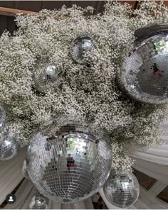 a bunch of disco balls hanging from the ceiling with baby's breath flowers in them