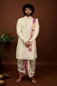 Off-white pattu kurta featuring floral embroidery on the neckline and sleeve hem. Paired with a contrast pink hem dhoti pant and a kanduva. - Aza Fashions Pancha Kattu Men, Off White Embroidered Set With Traditional Drape, Off White Embroidered Sets With Traditional Drape, Off White Traditional Drape Set With Embroidered Border, Traditional Wedding Sets With Embroidered Sleeves, Chanderi Traditional Wear With Embroidered Sleeves For Wedding, Unstitched Traditional Wear With Embroidered Sleeves For Wedding, Wedding Chanderi Sets With Embroidered Sleeves, Wedding Traditional Wear With Embroidered Sleeves In Chanderi