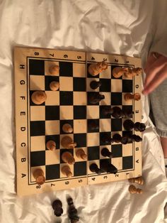 a man playing chess on top of a white sheet with black and brown pieces next to it