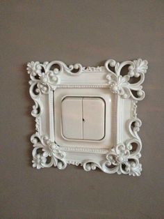 a white light switch sitting on top of a wall next to a brown wall with an ornate frame