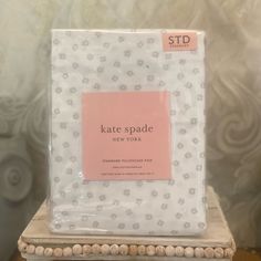 the package for kate spade new york sits on top of a small table in front of a wallpapered background