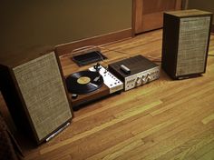 a record player and two speakers sitting on the floor in front of a speaker system