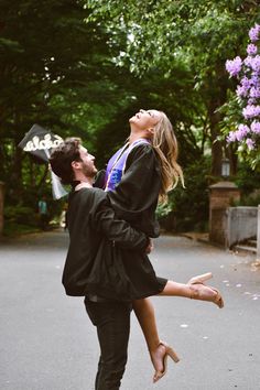 a man carrying a woman on his back in the middle of a road with trees