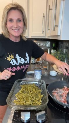 a woman standing in front of a pan filled with green beans