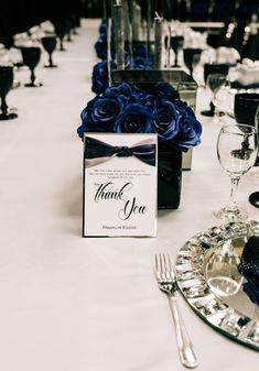 the table is set with silverware and blue roses