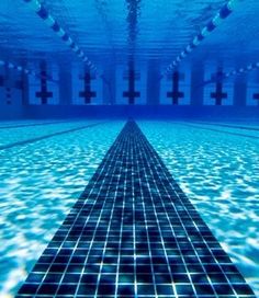 an underwater swimming pool with tiled floor and blue water surrounding the tiles is seen in this image