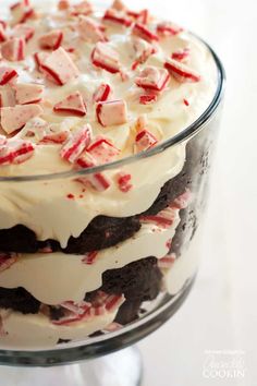 a close up of a cake in a glass dish on a white table with red and white icing