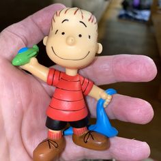 a hand holding a small toy with a boy on it's thumb and a blue shovel in his other hand