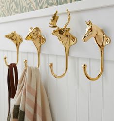 three gold hooks on the wall with towels hanging from them