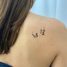 the back of a woman's shoulder with two butterflies on it