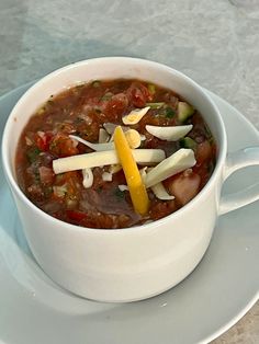 a white bowl filled with soup on top of a plate