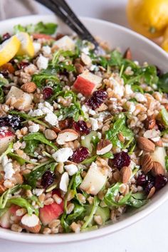 a white bowl filled with salad next to lemons