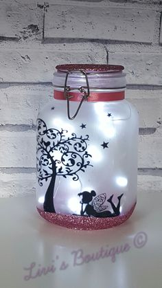 a glass jar with a tree painted on it and some string hanging from the lid