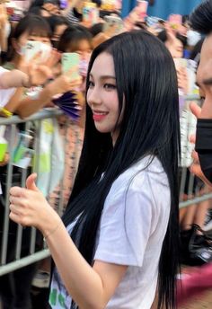 a woman with long black hair standing in front of a crowd