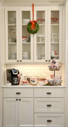 a kitchen with white cabinets and christmas decorations