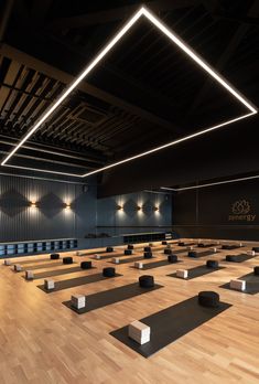 an empty gym with rows of yoga mats on the floor and lights hanging from the ceiling