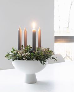 a white bowl filled with candles sitting on top of a table