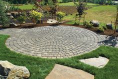 a circular brick patio surrounded by grass and rocks