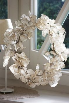 a wreath made out of white flowers sitting on top of a table next to a window