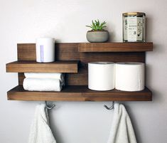 two wooden shelves holding toilet paper and other bathroom items on top of each shelf, along with a potted succulent plant