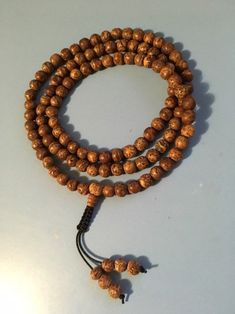 "Bodhi seed mala necklace made of 108 12mm beads with a Bodhi seed guru bead and an adjustable knot that allows you to change the length and tightness of the beads. Bodhi seeds are usually not polished so they are a solid color with small ridges or veins. Bodhi in Sanskrit translates to \"enlightened\" or \"awakened,\" therefore the Bodhi seed means \"enlightened seed.\" Bodhi is also a term in Buddhism to reflect a Buddha's understanding of the true nature of things. Many Buddhist wear the Bodh Adjustable Holistic Mala For Meditation, Adjustable Spiritual Mala For Puja, Traditional Beaded Bracelets For Meditation With 108 Beads, Bohemian Adjustable Mala For Puja, Adjustable Traditional Mala For Healing, Bohemian Mala With 108 Round Beads, Traditional Adjustable Mala For Healing, Spiritual Round Mala For Meditation, Bohemian Mala With 108 Beads