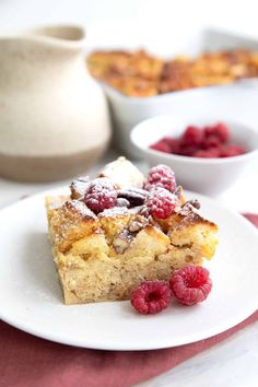 a white plate topped with dessert next to bowls of raspberries and other food