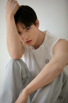 a young man sitting on the floor with his hands behind his head