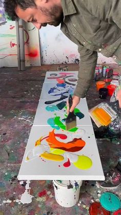 a man is painting on an easel with paint and watercolors in front of him