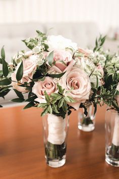 three vases filled with pink and white flowers on top of a wooden table next to each other