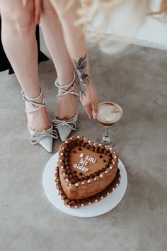 a woman standing next to a heart shaped cake on top of a white platter