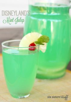 two glasses filled with green liquid on top of a wooden table