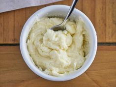 a white bowl filled with mashed potatoes on top of a wooden table