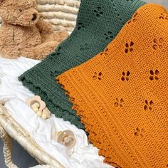 two teddy bears sitting next to each other on a bed with blankets and crocheted bedspreads