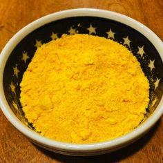 a bowl filled with yellow powder on top of a wooden table