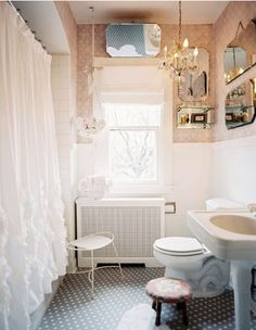 a white toilet sitting next to a sink in a bathroom under a window with curtains