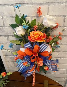 an orange and blue bouquet on top of a wooden table next to a brick wall